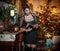 Beautiful woman in elegant black dress with Xmas tree in background. Portrait of fashionable blonde girl holding a book