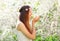 Beautiful woman enjoying smell spring flowers over flowering