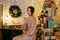 Beautiful woman in evening dress sitting with glass of champagne in decorated room with heap of christmas gifts