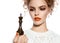 Beautiful woman with evening make-up holding a king chess piece