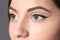 Beautiful woman with eyeliner on grey background, closeup