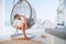 Beautiful woman in fancy black sunglasses lying in a comfortable hanging chair on the open house terrace and enjoying lazy middle