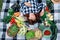 Beautiful woman farmer dressed in a shirt with closed eyes lying on a plaid among fresh organic vegetables. Top view. Copy, empty