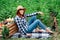 Beautiful woman farmer in a straw hat sitting on a blanket near fresh organic vegetables in a wooden box against the background of