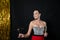 a beautiful woman in a festive dress stands with a glass of champagne at a black background with tinsel