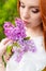 Beautiful woman with fiery red hair in the garden with lilac and white dress with beautiful makeup