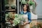 Beautiful woman florist shows fresh plants in flower studio