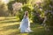 Beautiful woman in flying airy blue dress in blooming lilac garden.