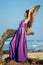 Beautiful woman with flying long butterfly violet purple dress posing on beach