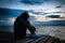 Beautiful woman in frustrated depression sitting on wooden bridge, near the beach on sunset. Concept