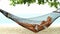 Beautiful woman full of vitality reclining suntanning in a hammock