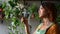 Beautiful woman gardener posing with green plant while standing at house room spbd.