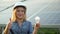 Beautiful woman in glasses and hard hat with lamp on the background of solar panels. The future is today