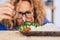 Beautiful woman with glasses looking with disgust some vegetables and rise on the table - she is going to eat healthy to feel