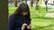 Beautiful woman in glasses uses cell smartphone outdoors in the park - detail . Young attractive happy girl relaxes in