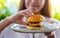 A beautiful woman grabbing and eating beef hamburger in a plate