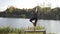 Beautiful woman with great silhouette warming up for yoga poses in nature in the morning next to a lake in slow motion -