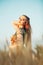 Beautiful woman in green dress on field with sheaf of wheat in hand at sunset light, girl enjoying summer nature landscape,