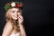 Beautiful woman in green fir crown on dark background. Happy girl with blonde hair and Xmas wreath