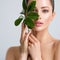 Beautiful woman with green leave near face and body.  Closeup girl`s face with green leave. Skin care beauty treatments concept