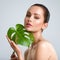 Beautiful woman with green leave near face and body.  Closeup girl`s face with green leave. Skin care beauty treatments concept