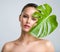 Beautiful woman with green leave near face and body.  Closeup girl`s face with green leave. Skin care beauty treatments concept