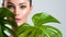 Beautiful woman with green leave near face and body.  Closeup girl`s face with green leave. Skin care beauty treatments concept