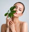 Beautiful woman with green leave near face and body.  Closeup girl`s face with green leave. Skin care beauty treatments concept