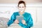 Beautiful woman with green nightie and white facial mask resting on bed and holding tablet before sleeping.