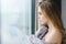 Beautiful woman in grey knitted coverlet looking out of window