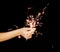 Beautiful woman hands holding sparkler lights in front of black