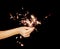 Beautiful woman hands holding sparkler lights in front of black