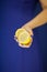 Beautiful woman hands with perfect nail polish holding lemon, yellow fruit on blue