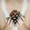 Beautiful woman hands with turquoise nail polish art holding fir cone