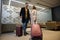 Beautiful woman and handsome man with suitcases traveling together, waiting to board a flight in airport VIP lounge