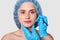 Beautiful woman has marked arrows under eyes. Lady wants to improve her appearance. Plastic surgeon with blue gloves draws black