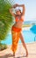 Beautiful woman in a hat, in a orange swimsuit a palm tree.