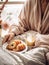 Beautiful woman having breakfast in bed, home bedroom interior with bright morning light, healthy food on cozy decorated