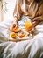 Beautiful woman having breakfast in bed, home bedroom interior with bright morning light, healthy food on cozy decorated