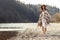 beautiful woman hipster walking on river beach in mountains, having fun and enjoying, boho travel concept, space for text