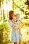 Beautiful woman hold little baby girl in caring arms, walking at the park, hugging, lovely mother kissing adorable