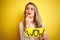 Beautiful woman holding amazed wow surprise banner over isolated yellow background serious face thinking about question, very