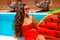 Beautiful woman Holding Glass coctail by watermelon float mattress swimming pool on villa resort. Sexy girl enjoy summer vacation