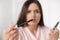 Beautiful woman holding mascara brush with fallen eyelashes indoors