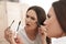 Beautiful woman holding mascara brush with fallen eyelashes near mirror