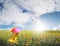 Beautiful woman holding multicolored umbrella in sunflower field and cloud sky