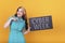 Beautiful woman holding and pointing a Cyber Week sign over a yellow background