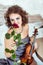 Beautiful woman holding a violin and smelling red rose