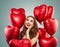 Beautiful woman holds red heart balloons. Surprise, valentines people and Valentine`s day concept . Expressive facial expressions