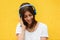 Beautiful woman joyful listening to music on headsets. Yellow background